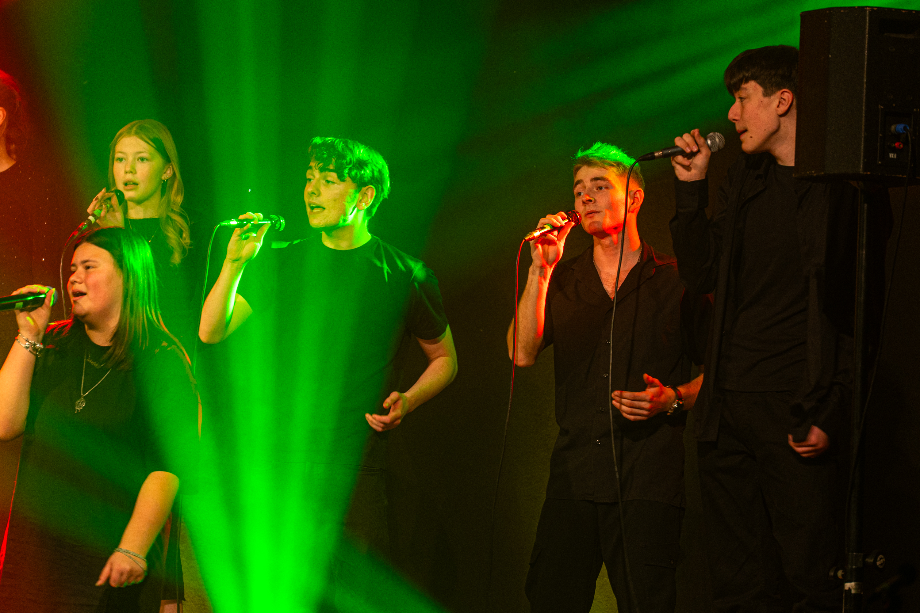 Drenge og piger fra ungdomskor står på scenen og synger