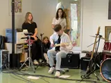 Dreng fra talentklassen spiller på guitar og tre andre unge står bag ved og ser på ham