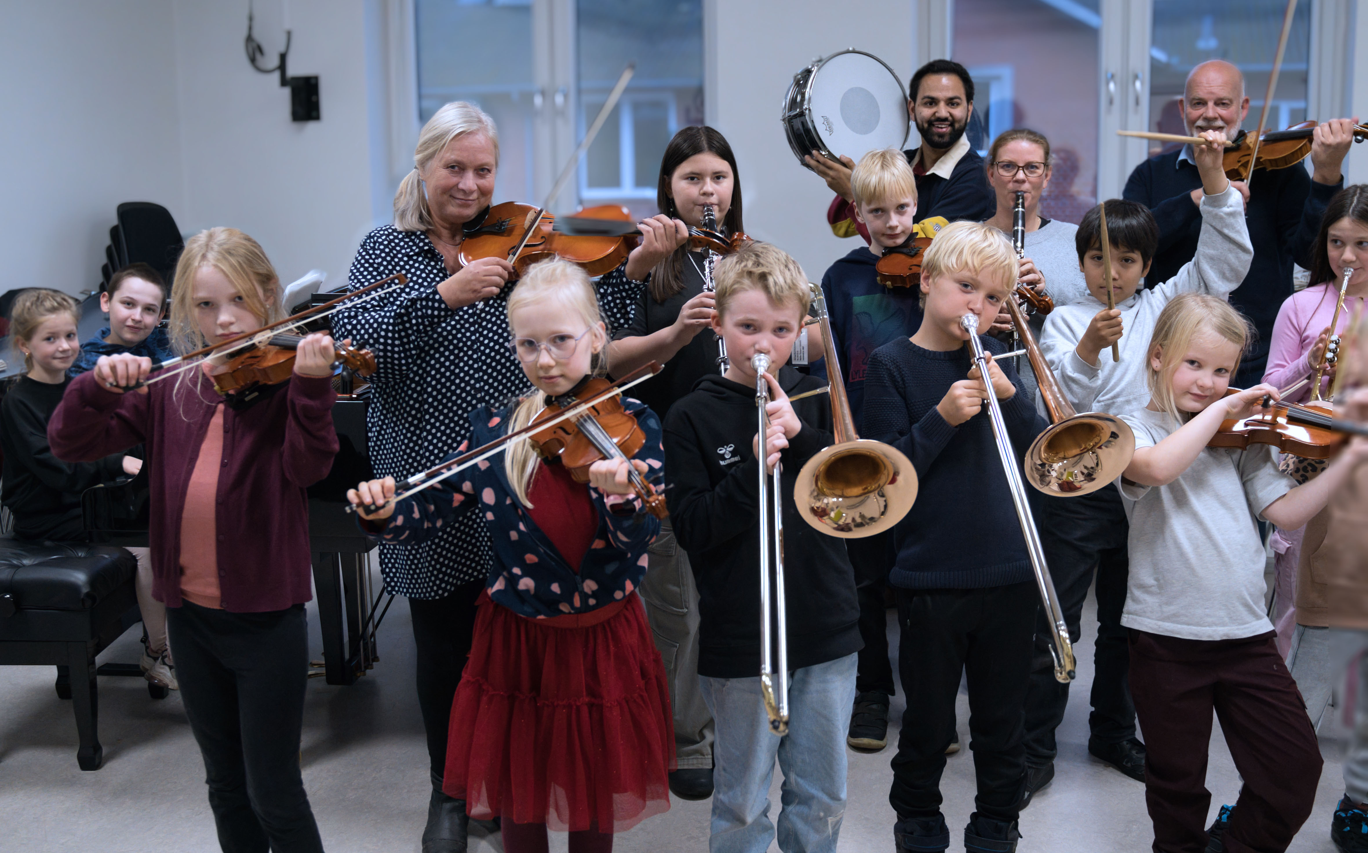 Børn og voksne står med deres instrumenter i hånden